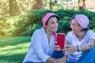 Two smiling young adult women with a pink headscarf taking a selfie. 2 warrior sisters laughing and...