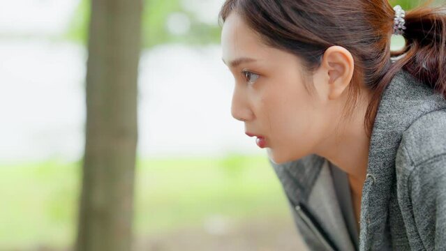Asian woman wearing jacket and tired engaged in fitness in public park. Her gaze was determined to lose weight. Healthy lifestyle activity concept