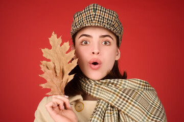 Autumn woman, isolated studio portrait. Funny young girl with autumn fall leaves. Season hat, scarf.