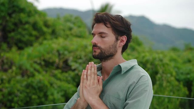 Portrait of a handsome and peaceful dark-haired Caucasian bearded man, whispering a prayer in a quiet voice, while praying to God, being in peace of mind. Mindfulness. Spiritual growth. Awakening