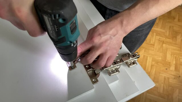 Cordless combi drill for assembly the furniture door hinges ot he wooden furniture made of particle board. Medium Density Fiberboard (MDF). Woodworking industry and furniture assembly concept