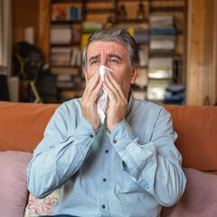 Sick man with a cold and sneezing through the cold of winter in his house.