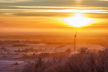 Wind turbine in a winter landscape at sunset