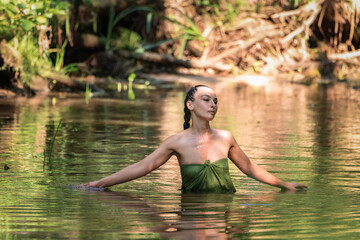 Portrait of a young beautiful dark-haired girl posing in the river.