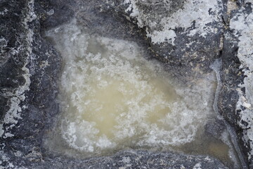 closeup of salt drying in a puddle by the lava rocks  on the island of la réunion
