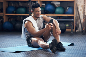 Man, exercise and phone on social media with smile rest on floor in gym during training session....
