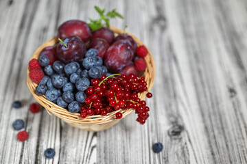 Summer composition. Wicker basket with fruits and berries. Wooden background, shallow depth of field.