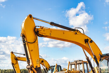 Powerful excavator at a construction site against a blue cloudy sky. Earthmoving equipment for construction. Development and movement of soil.