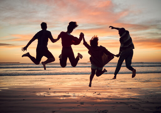 Friends, silhouette and jump on the beach during sunset on vacation together. Excited people on travel holiday in summer with fun, play and friendship in hawaii with group during journey or trip
