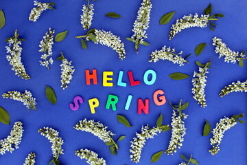 The inscription "Hello, spring with bird cherry flowers" is laid out on a blue background.