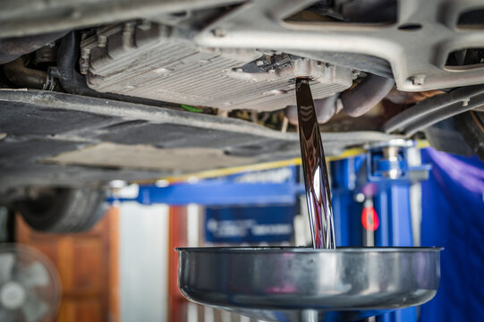 Auto mechanic draining automotive engine oil ,engine oil change service.