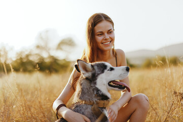 Woman and her husky dog happily stroll through the grass in the park smile with teeth fall sunset...