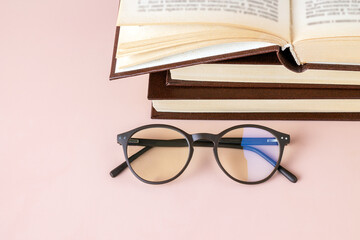 polarized glasses and a stack of books on a pink background, copy space