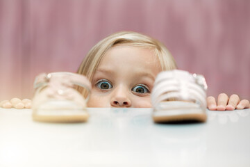 Girl, shoes and shopping with a child customer deciding between footwear for fashion, style or consumerism. Children, retail and option with a kid looking at a sandle and comparing for her wardrobe