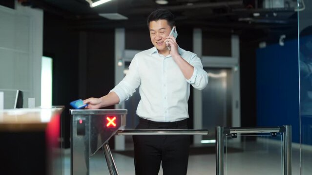 Man worker walks through a Automatic security turnstile station in office. employee entrepreneur pass over in coworking space. Enter the business center indoors. holding electronic entrance gate card