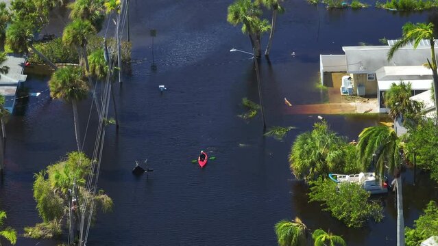 Kayak boat floating on flooded street surrounded by hurricane Ian rainfall flood waters homes in Florida residential area. Consequences of natural disaster