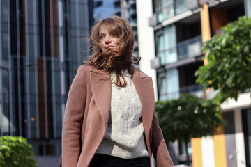 Street photo session of a girl with blond long hair in a beige coat. Photo shoot in the big city.