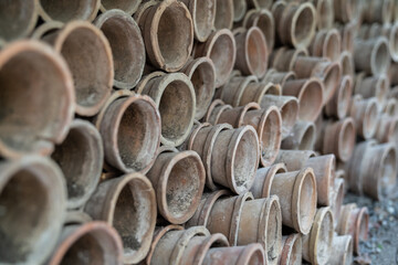 Closeup of stacks of old used weathered terra cotta flower pots in gardening shed. Empty vintage flowerpots.