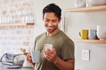 Phone, coffee and social media with a man in his kitchen in the morning while reading a message in his home. Mobile, internet and tea with a handsome young man sending a text from his house in India