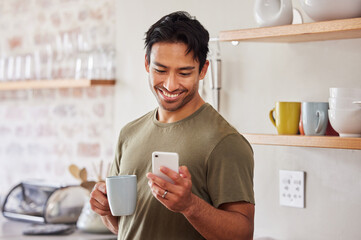 Phone, coffee and social media with a man in his kitchen in the morning while reading a message in his home. Mobile, internet and tea with a handsome young man sending a text from his house in India - Powered by Adobe