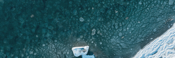 Top view of the freezing sea. Aerial view of ice floes in sea water near an icy seashore. Nature of...