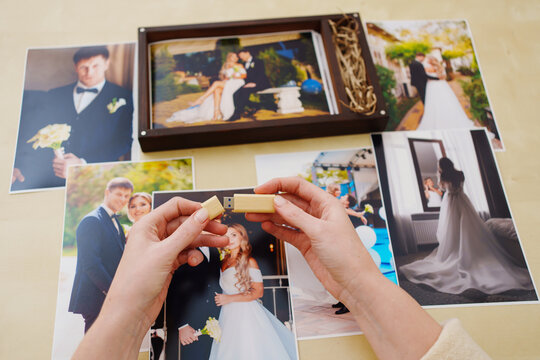 printed wedding photos, a wooden box and hands with a flash drive