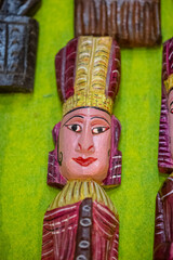 Handmade colorful tribal look face mask souvenir hanging on plain background. Selective focus on object.