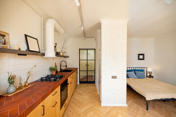 Interior of stylish studio apartment with kitchen and bedroom in white and beige tones in loft style