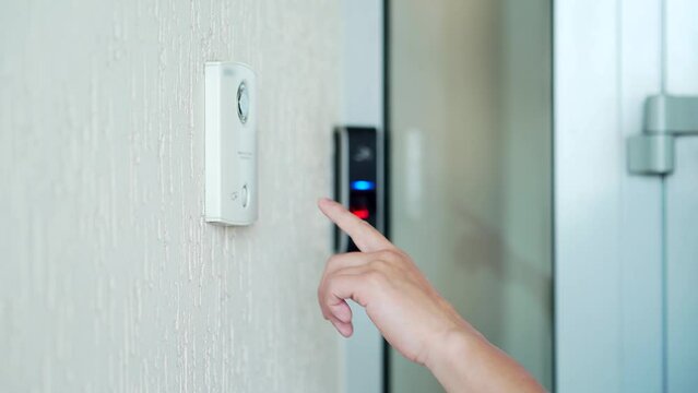 Close-up male hand finger presses the intercom button doorbell Remote call to the apartment or office to open the door Using notifications when a guest arrives man opens the door by entering Closeup