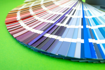 Color guide close up. Assortment of flowers for design. Color palette fan on green background A graphic designer selects colors from a color palette guide.