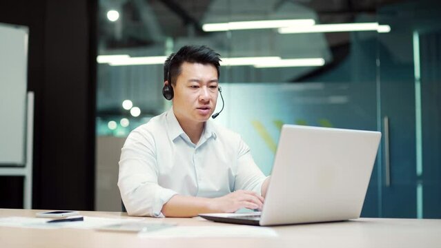 Asian teacher consultant lecturer in suit holds online video meeting consultation conference sitting at workplace in office using laptop computer writes in notebook. training, virtual webinar. Asia