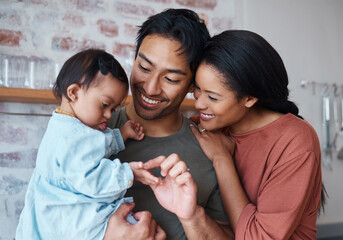 Family with down syndrome baby, happy parents in kitchen home together and young child care. Indian father holding cute kid, asian mother smile with support and bonding happiness in Brazil house