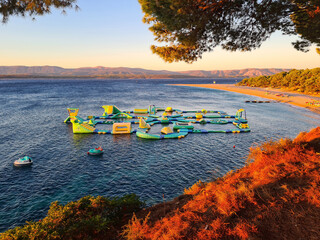 Aquapark &quot Zlatni Rat&quot  in Bol, Dalmatië, Kroatië. Een opblaasbare speeltuin in de Adriatische Zee, net om de hoek van het beroemde strand &quot Zlatni Rat&quot , dat rechts op de achtergrond te zien is.