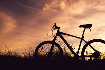 bicycle silhouette against the background of the sunset sky and blurry clouds