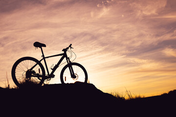 Fototapeta na wymiar bicycle in a dark key against the sky. blurry clouds during sunset on high ground