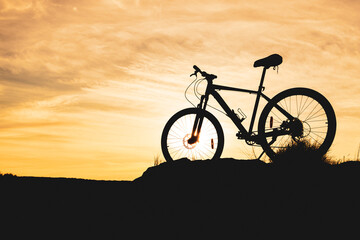 Fototapeta na wymiar against the background of a blurred sunset sky, the silhouette of a bicycle