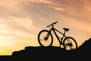 silhouette of a bicycle on a mountain, the background is a blurred sky in the evening