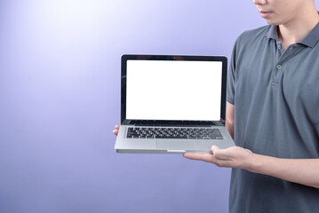 Fototapeta na wymiar Man holding laptop with blank screen on purple background.