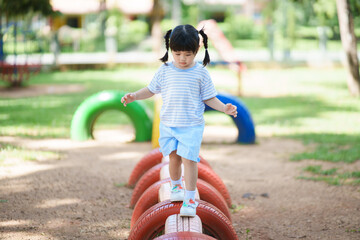 Cute asian girl smile play on school or kindergarten yard or playground. Healthy summer activity for children. Little asian girl climbing outdoors at playground. Child playing on outdoor playground.