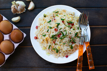 Fried rice on a dark wooden floor. Thai food. One dish Cutlery, side dishes, spices, chicken eggs.