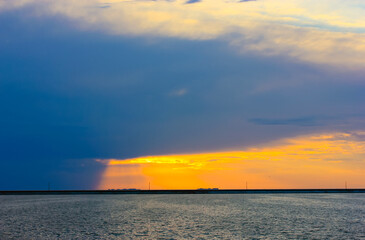 A storm at sea. A blue rain cloud hung in the sky over the blue sea at sunset in the evening. The...