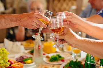 hands with glasses of drinks above the festive table. 
