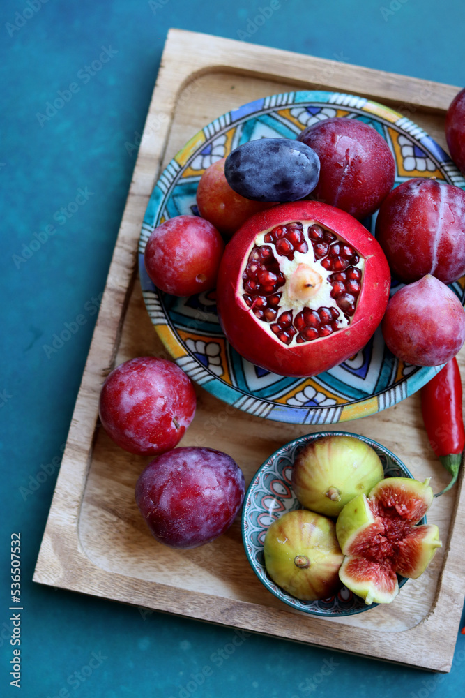 Poster Still life with fresh Israeli fruits on a blue ceramic plate. Colorful picture of juicy fruit. 