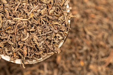 Large-leaf black tea in a glass and scattered on the table. Close-up of the surface texture