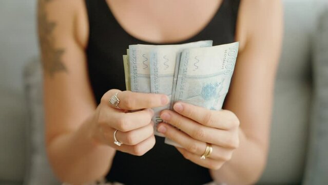 Young woman counting chile pesos banknotes at home