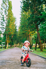 Baby boy riding  balance bike in park