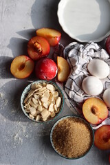 Sweet cake ingredients on a table. Close up photo of plums, eggs, brown sugar and almonds. Baking  fruit pie. Healthy eating concept. 