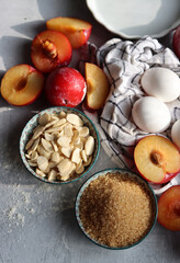 Fototapeta premium Sweet cake ingredients on a table. Close up photo of plums, eggs, brown sugar and almonds. Baking fruit pie. Healthy eating concept. 