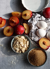 Plum pie in process. Fresh ingredients on a table. Top view photo of plums, almonds, demerara sugar, eggs. Sweet cake ingredients closes up. 
