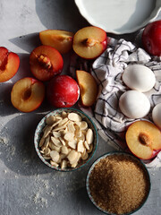 Sweet cake ingredients on a table. Close up photo of plums, eggs, brown sugar and almonds. Baking  fruit pie. Healthy eating concept. 